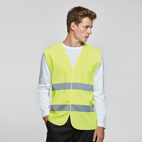 Hombre joven con chaleco de alta visibilidad amarillo y franjas reflectantes sobre camiseta blanca.