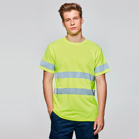 Hombre joven de pie con camiseta de alta visibilidad verde y franjas reflectantes